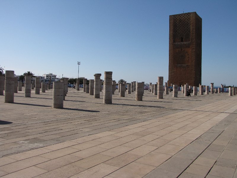 120312_hassan minaret.jpg - Aan de overzijde van het plein staat de Hassan minaret. Deze niet afgebouwde minaret hoort bij een moskee die ook nooit afgebouwd is. De sultan die in 1195 opdracht gaf voor de bouw overleed in 1199. De bouw is toen gestopt. De zuilen zijn het enige dat rest van de geplande moskee.